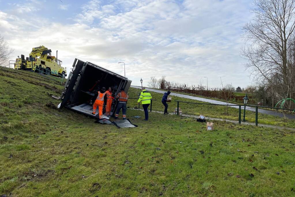 Vrachtwagen belandt op zijn kant onderaan dijk