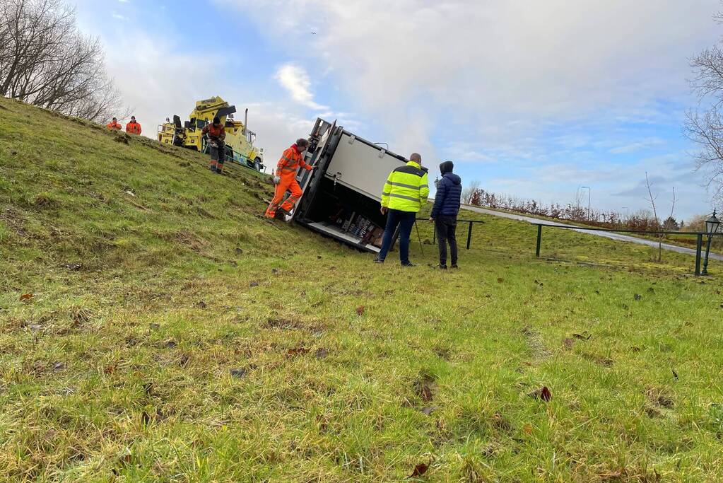 Vrachtwagen belandt op zijn kant onderaan dijk