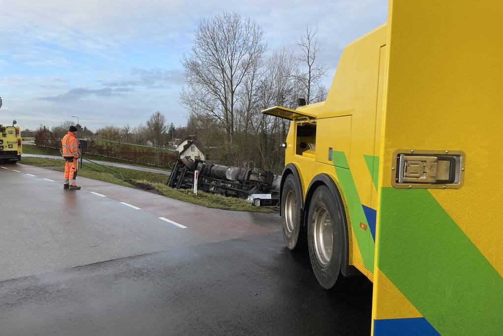 Vrachtwagen belandt op zijn kant onderaan dijk