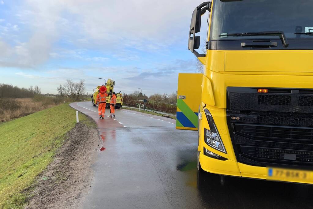 Vrachtwagen belandt op zijn kant onderaan dijk