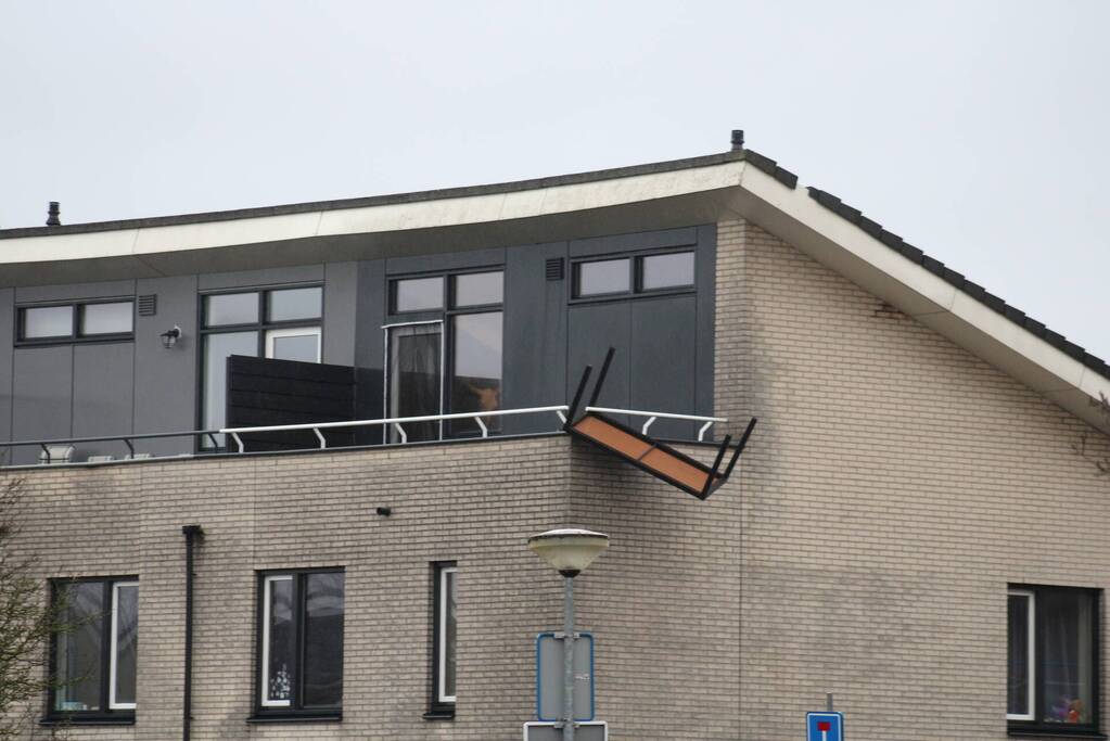Weggewaaide tafel hangt gevaarlijk over balkonrand