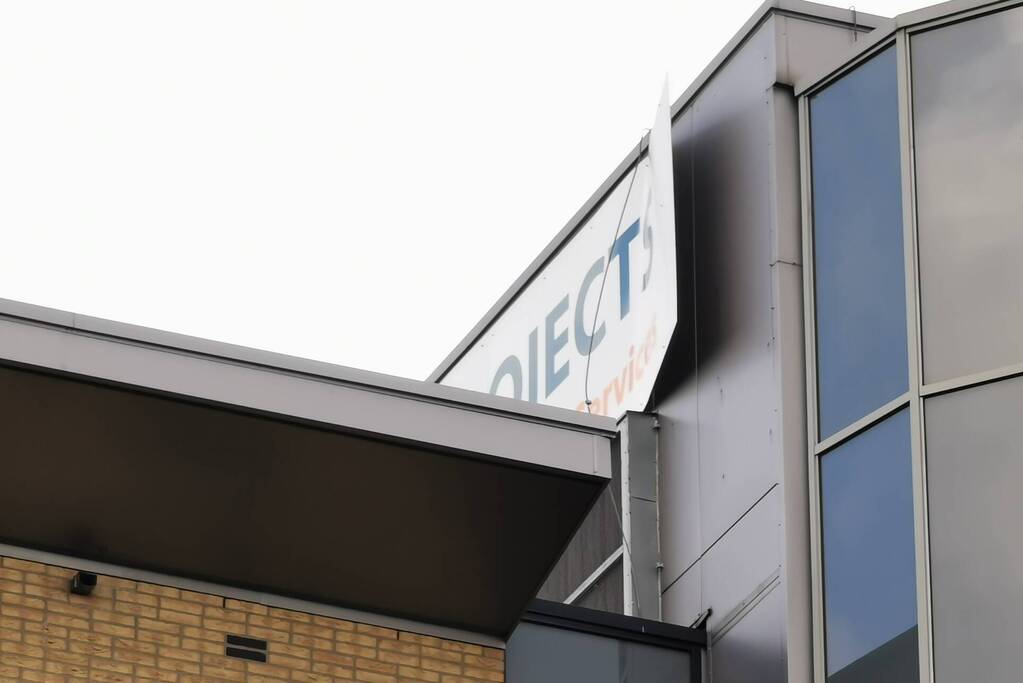 Bedrijfsbord waait los van kantoorpand