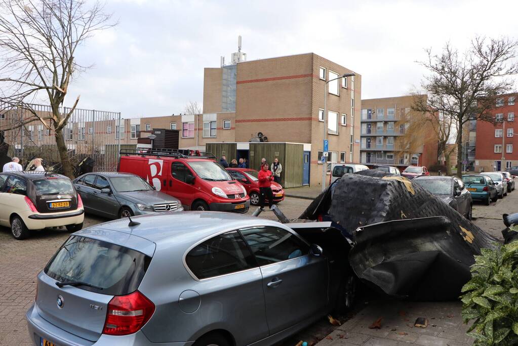 Dakbedekking van flat waait over auto's en lantaarnpalen