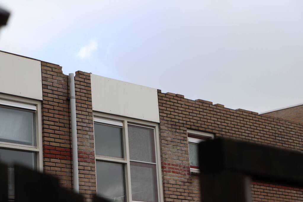 Dakbedekking van flat waait over auto's en lantaarnpalen