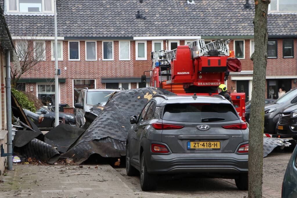 Dakbedekking van flat waait over auto's en lantaarnpalen