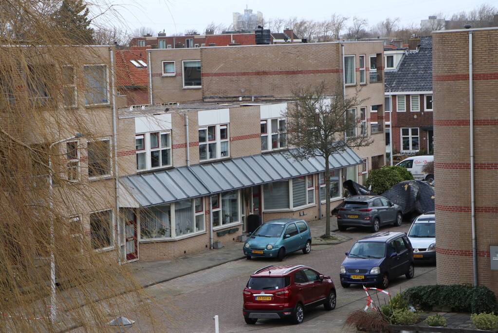 Dakbedekking van flat waait over auto's en lantaarnpalen