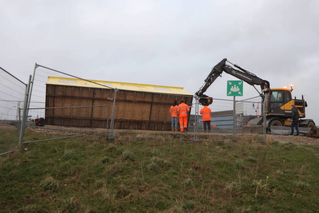 Bouwkeet waait om en belandt op wegdek