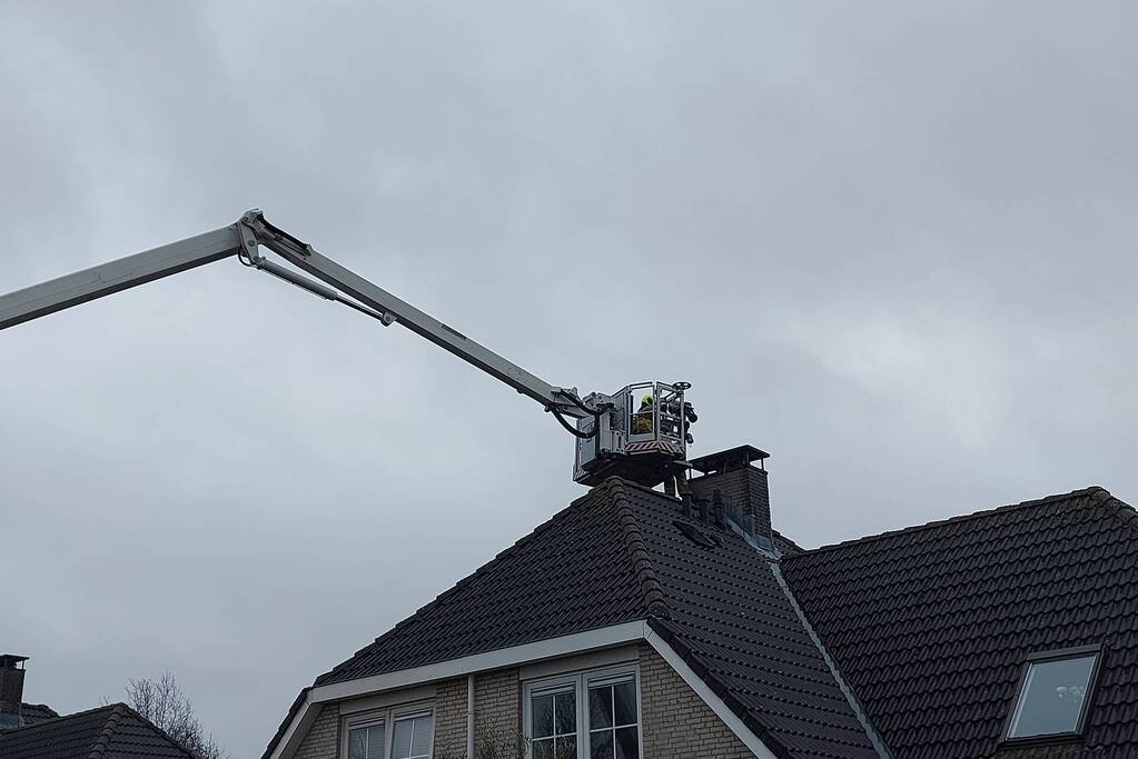 Brandweer verwijderd losse plaat op schoorsteen van woning