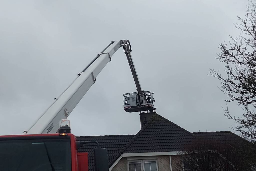 Brandweer verwijderd losse plaat op schoorsteen van woning
