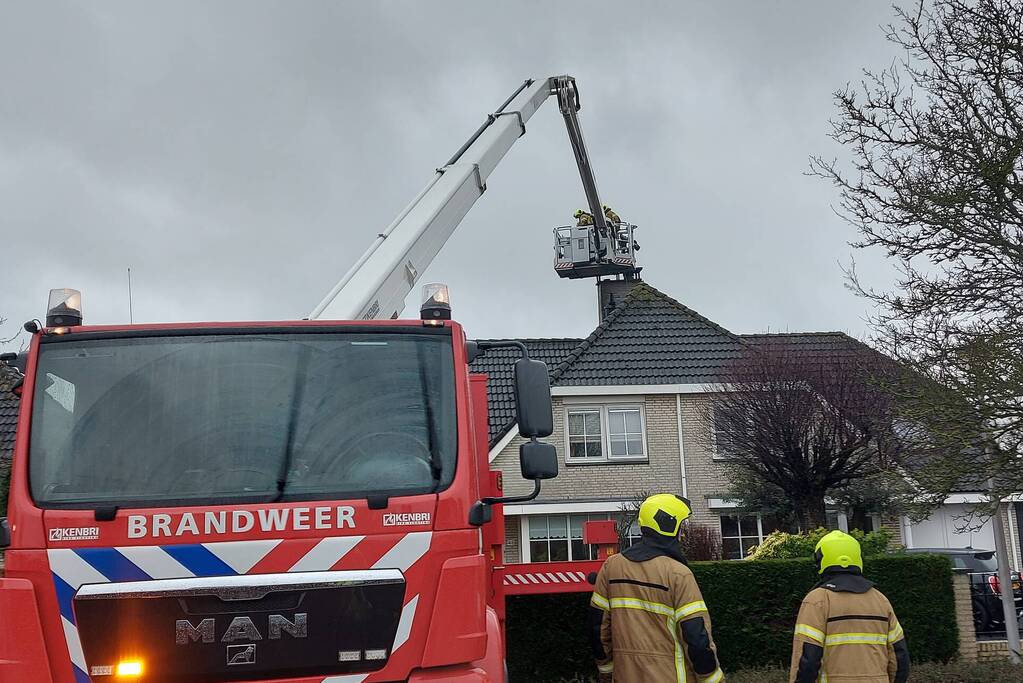 Brandweer verwijderd losse plaat op schoorsteen van woning