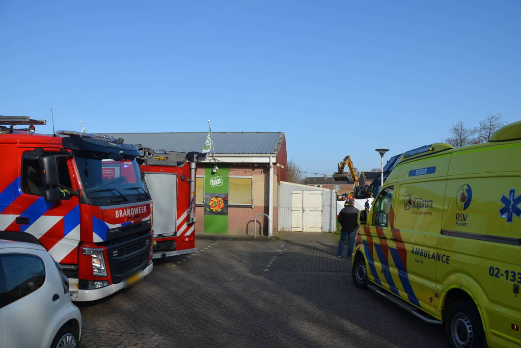 Persoon bekneld onder omgevallen graafmachine