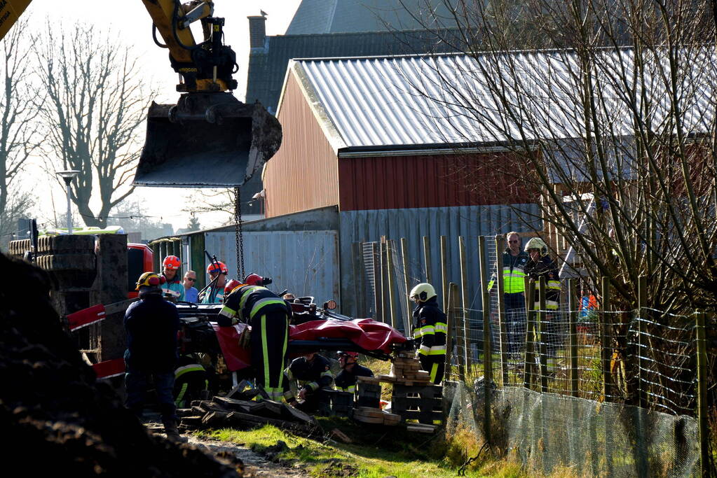 Persoon bekneld onder omgevallen graafmachine