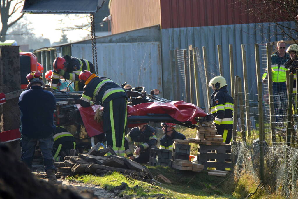 Persoon bekneld onder omgevallen graafmachine