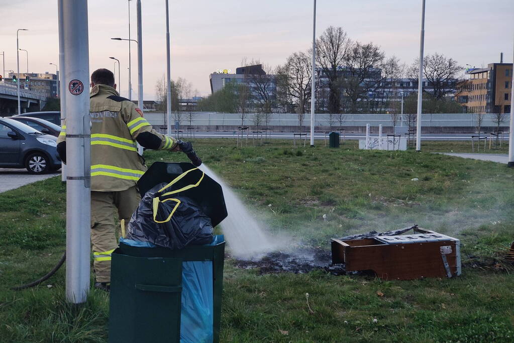 Brandweer blust brandende afvalcontainer