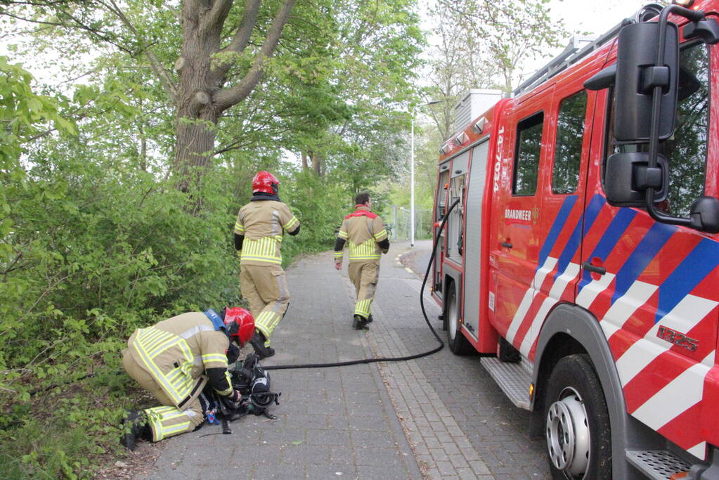 Vlammen bij brand naast sportveld