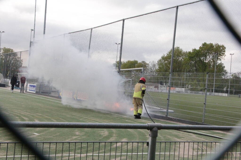 Vlammen bij brand naast sportveld