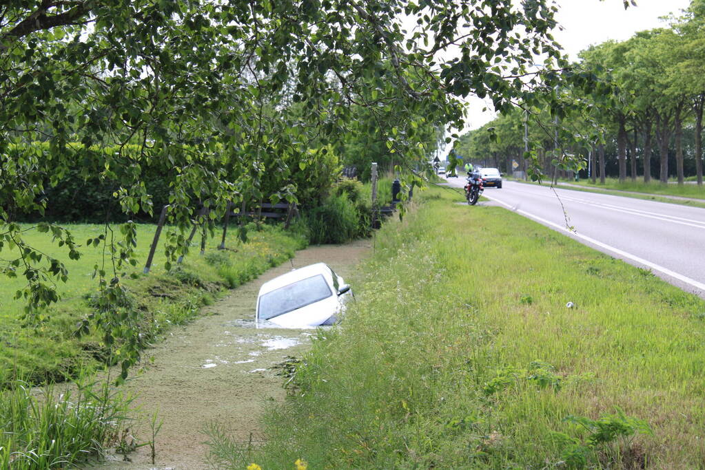 Personenauto raakt te water naast doorgaande weg
