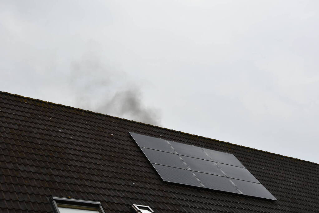 Veel rook uit zolderraam bij brand in woning