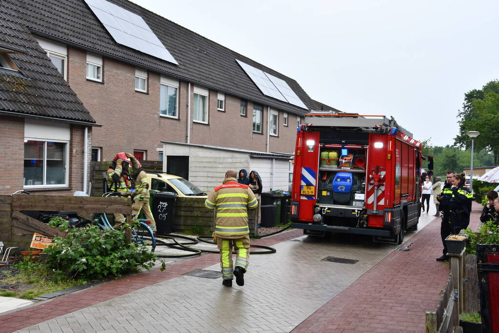 Veel rook uit zolderraam bij brand in woning