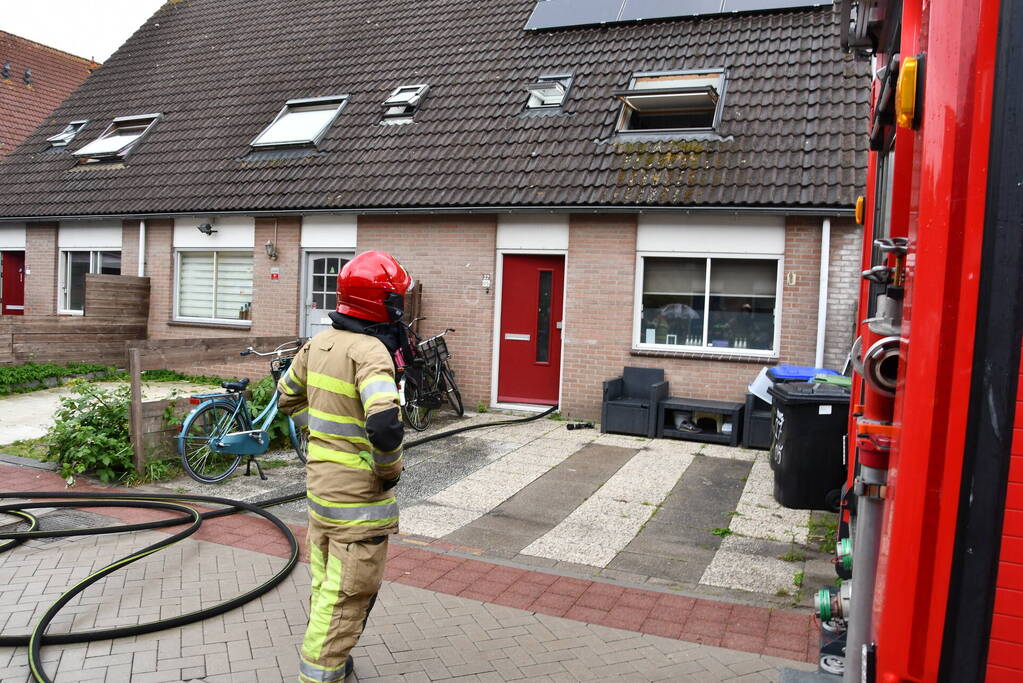 Veel rook uit zolderraam bij brand in woning
