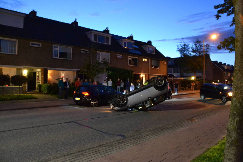 Auto op zijn kop na botsing met geparkeerde auto