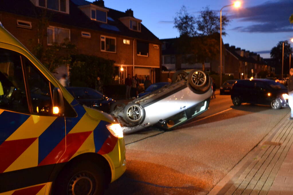 Auto op zijn kop na botsing met geparkeerde auto