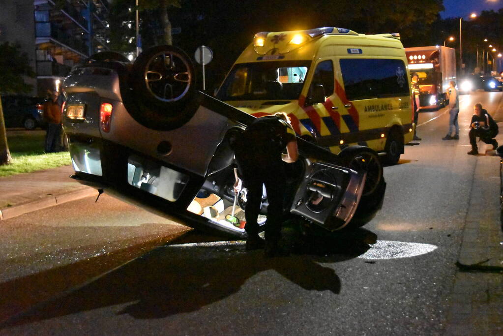 Auto op zijn kop na botsing met geparkeerde auto