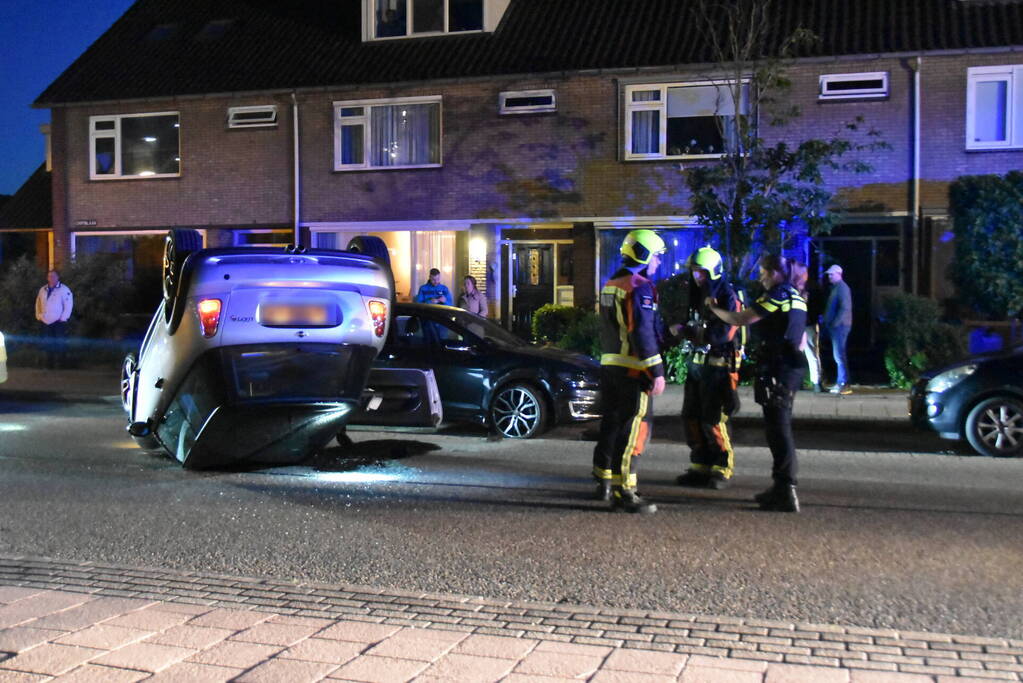 Auto op zijn kop na botsing met geparkeerde auto