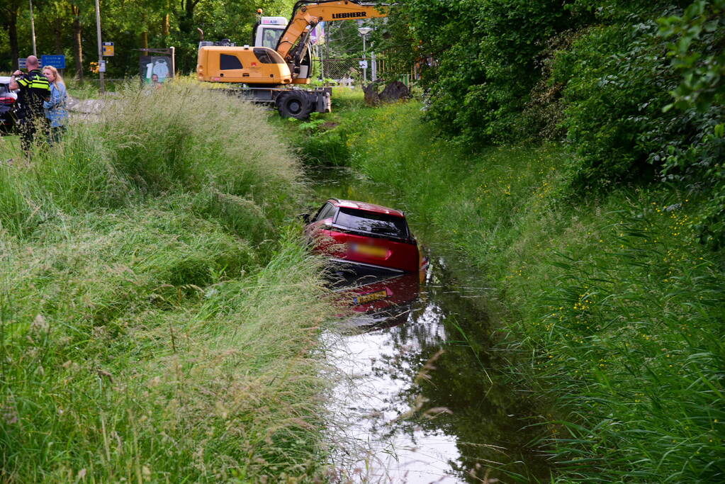 Auto rijdt over rotonde de sloot in