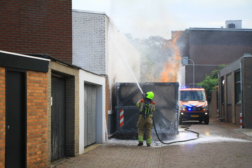 Vlammen slaan uit bouwcontainer met afval