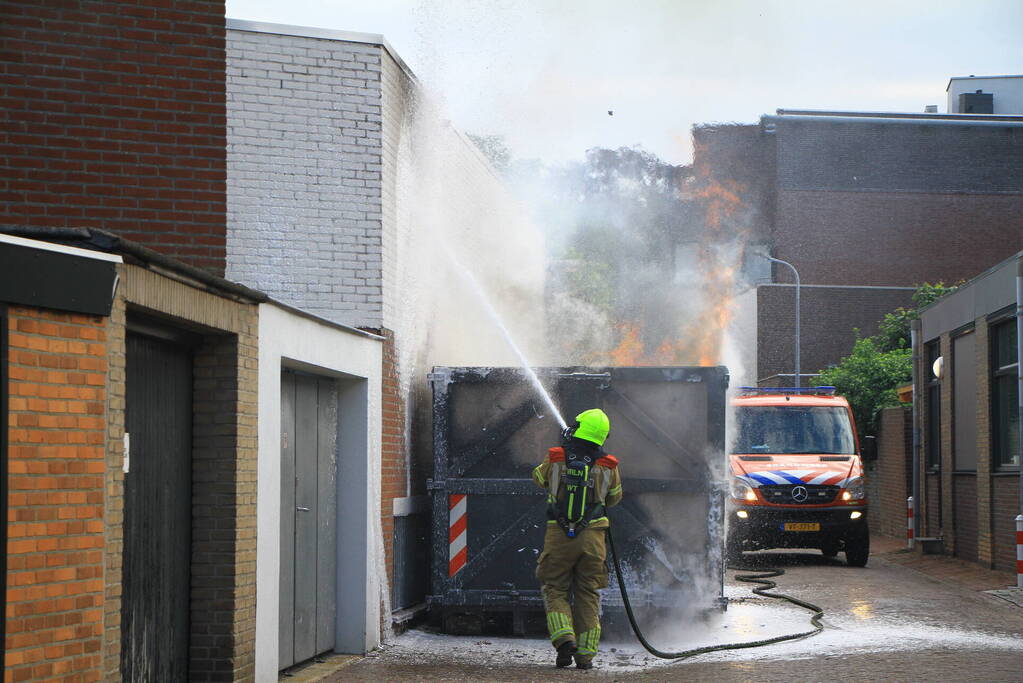 Vlammen slaan uit bouwcontainer met afval