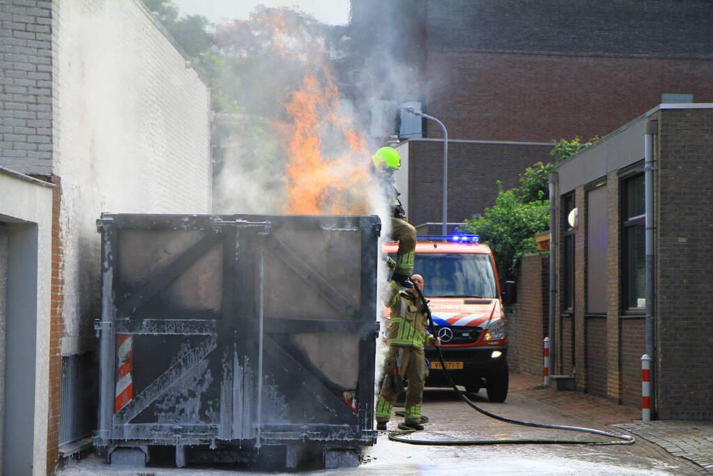 Vlammen slaan uit bouwcontainer met afval