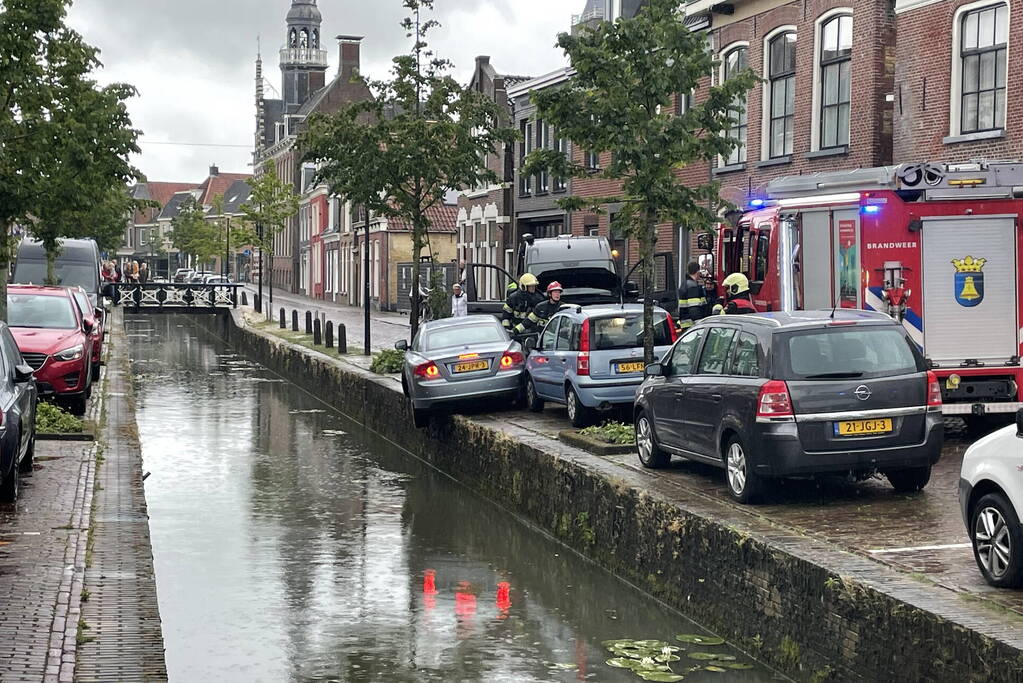 Auto bengelt op rand van gracht