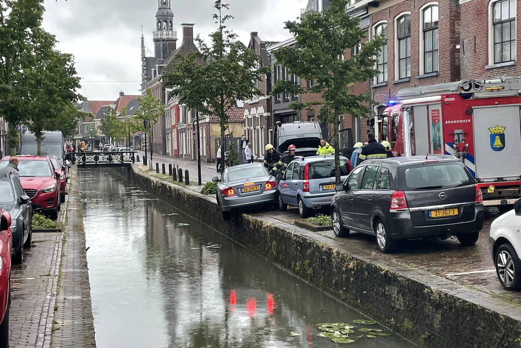 Auto bengelt op rand van gracht