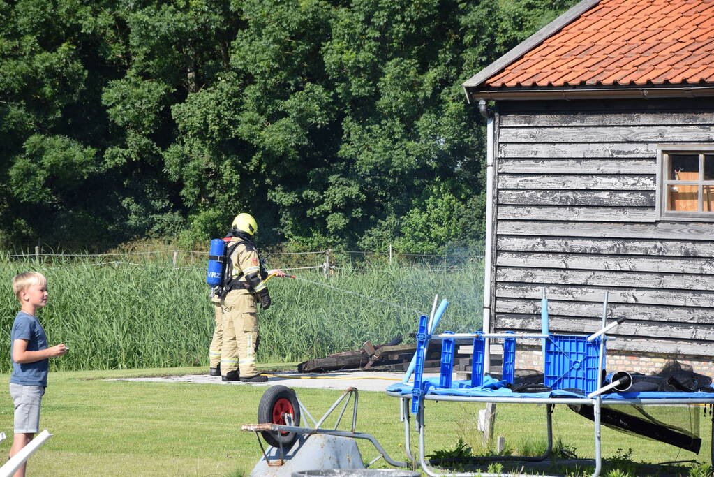 Houten balken achter schuur vlam gevat