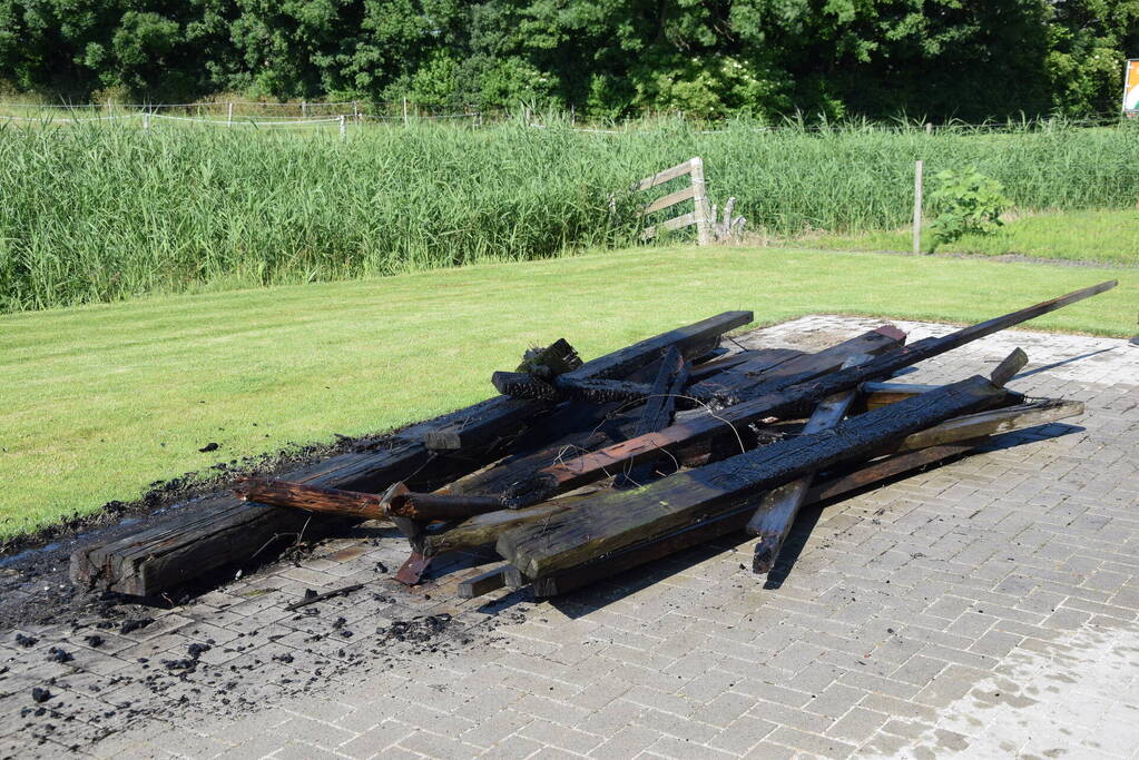Houten balken achter schuur vlam gevat