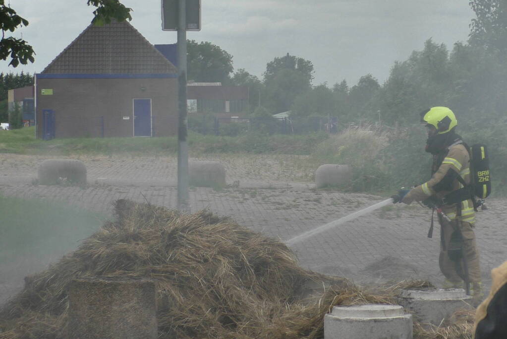 Brandweer blust brandende hooibaal