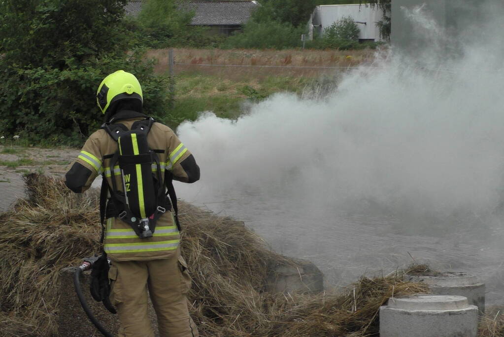 Brandweer blust brandende hooibaal