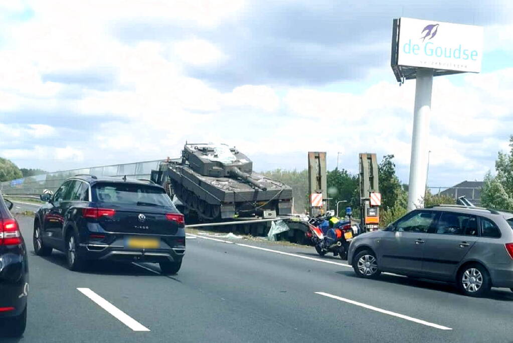 Vrachtwagen met gevechtstank boort zich in geluidswal