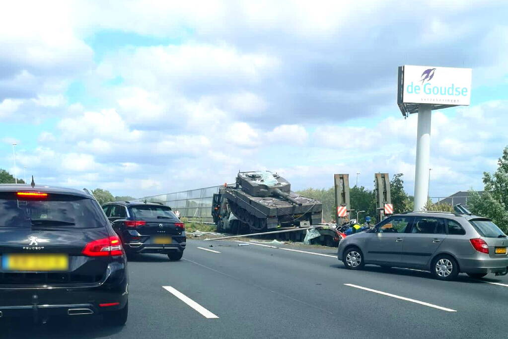Vrachtwagen met gevechtstank boort zich in geluidswal