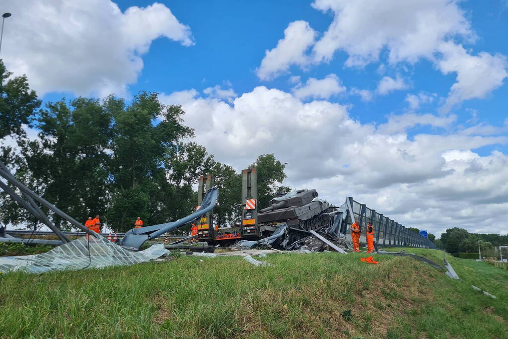 Vrachtwagen met gevechtstank boort zich in geluidswal