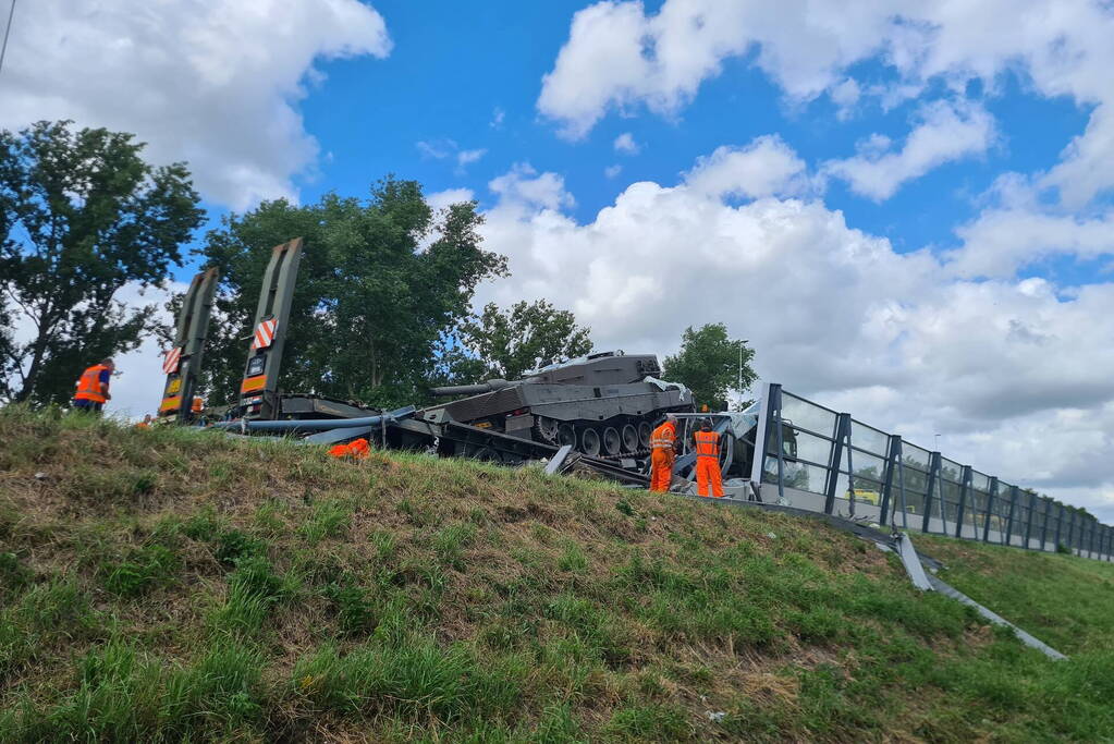 Vrachtwagen met gevechtstank boort zich in geluidswal