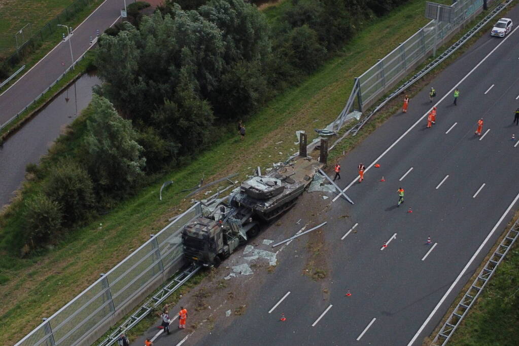 Vrachtwagen met gevechtstank boort zich in geluidswal