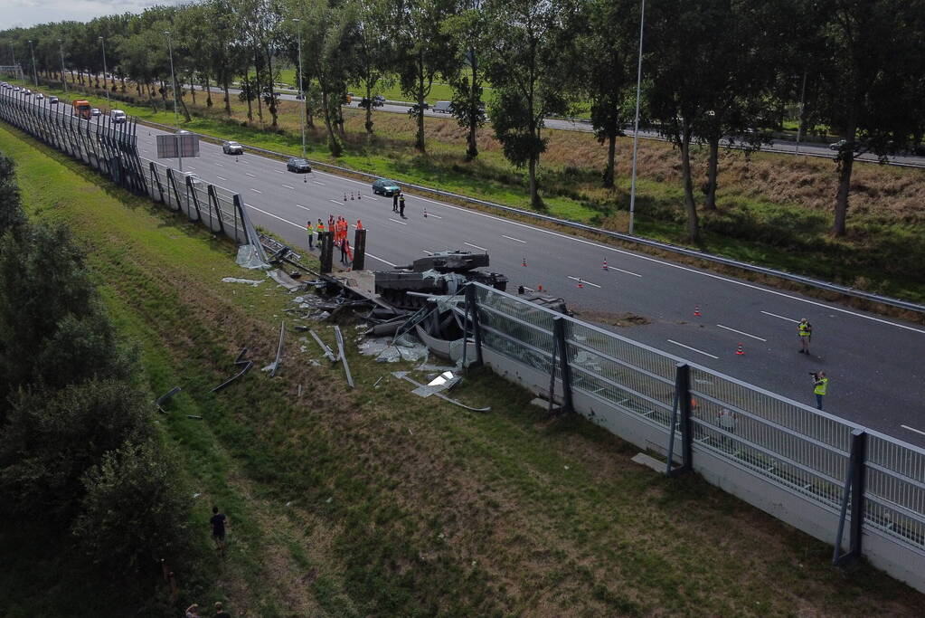 Vrachtwagen met gevechtstank boort zich in geluidswal