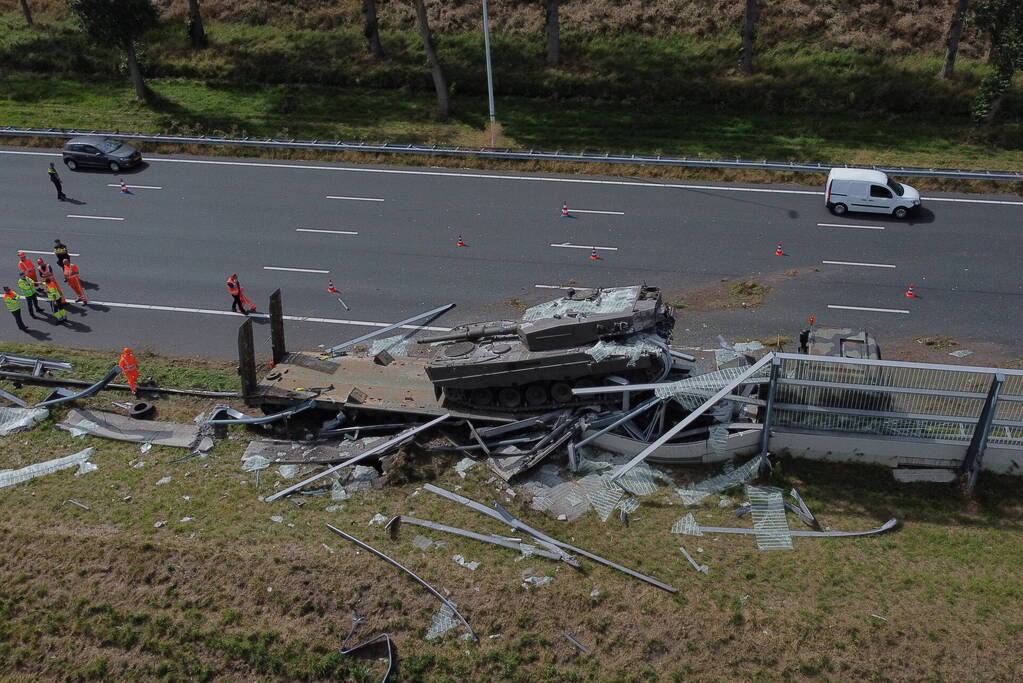Vrachtwagen met gevechtstank boort zich in geluidswal