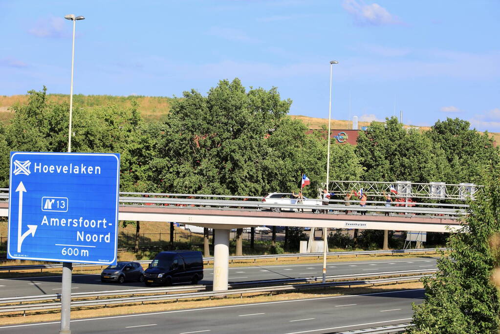 Verontrustende burgers staan met omgekeerde vlaggen zwaaien naar verkeer op A1