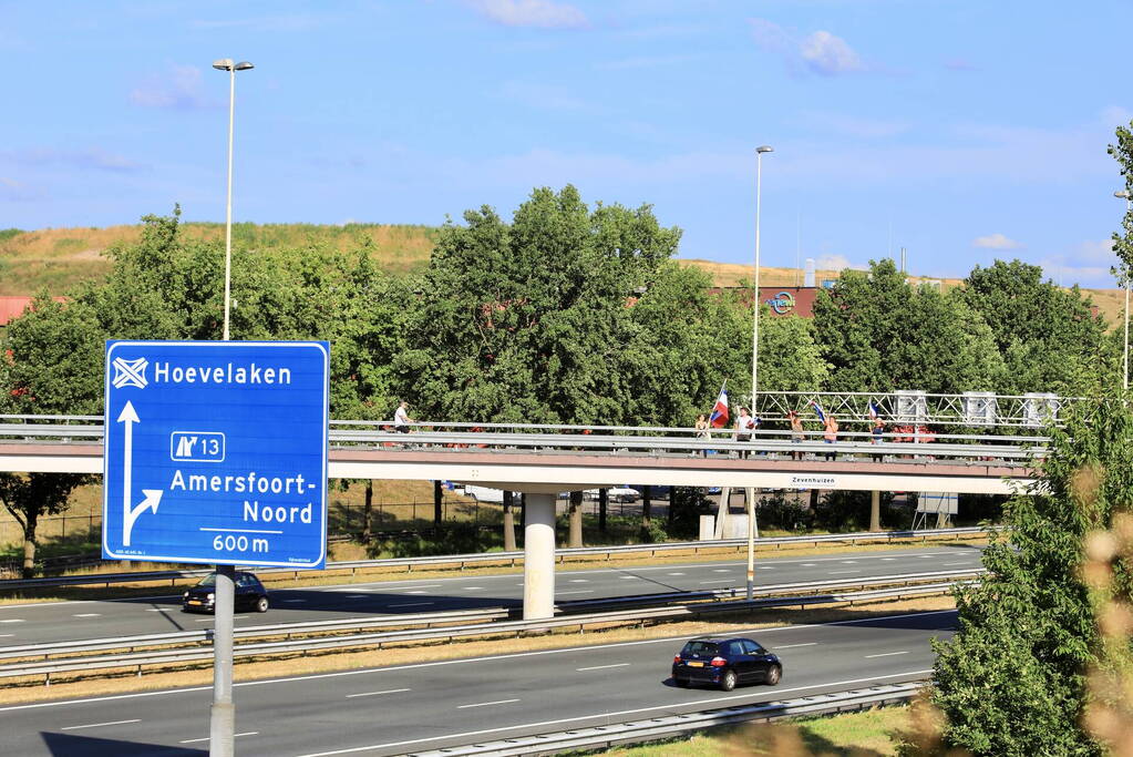 Verontrustende burgers staan met omgekeerde vlaggen zwaaien naar verkeer op A1
