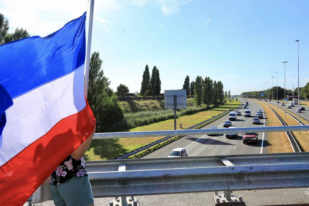 Verontrustende burgers staan met omgekeerde vlaggen zwaaien naar verkeer op A1
