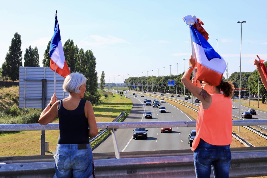 Verontrustende burgers staan met omgekeerde vlaggen zwaaien naar verkeer op A1