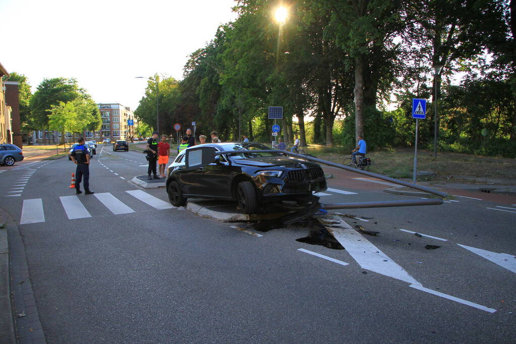 Personenauto uit de bocht, lantaarnpaal geraakt